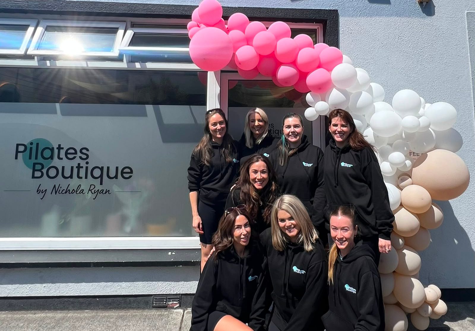 A group of pilates instructors, all in black uniforms, stand and crouch outside the new Pilates Boutique studio in Ballinasloe.
